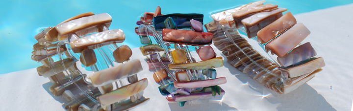 Parelmoer armbanden voor dames van echt parelmoer liggend in de zon op lichte ondergrond bij water