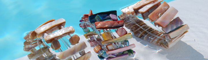Parelmoer armbanden in verschillende kleuren bij zwembad als zomer sieraden voor strand en stad.