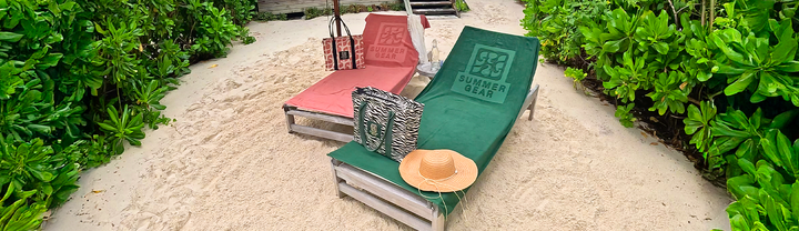Strandlakens op ligbedden bij het strand met strandtassen.