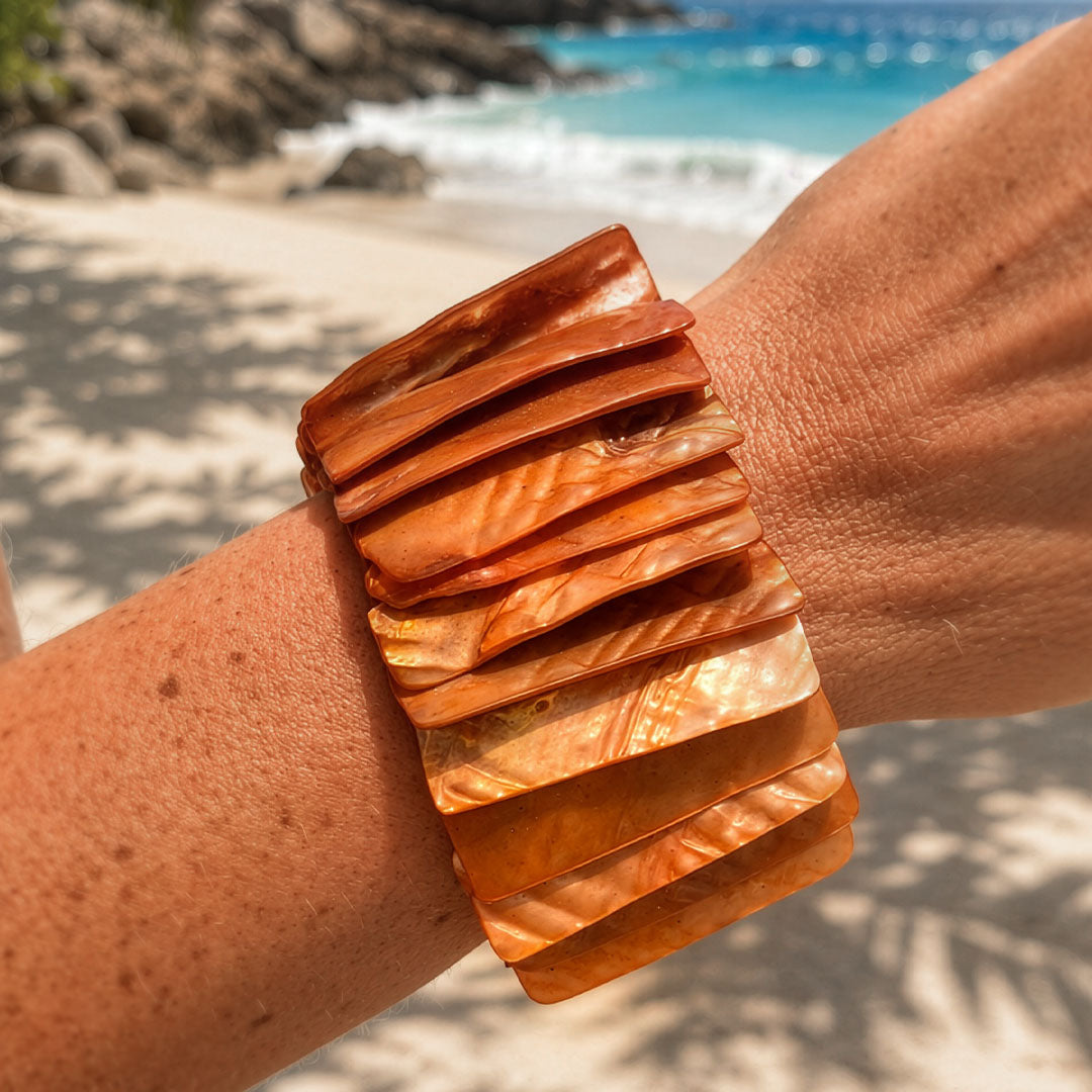 Parelmoer armband Amber Shell met brede oranjebruine schakels gedragen op het strand