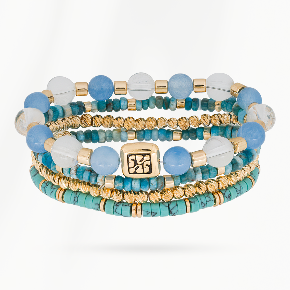 Blue Coast armbandenset van SummerGear met vier armbanden van blauwe, turquoise en witte kralen en goudkleurige details.
