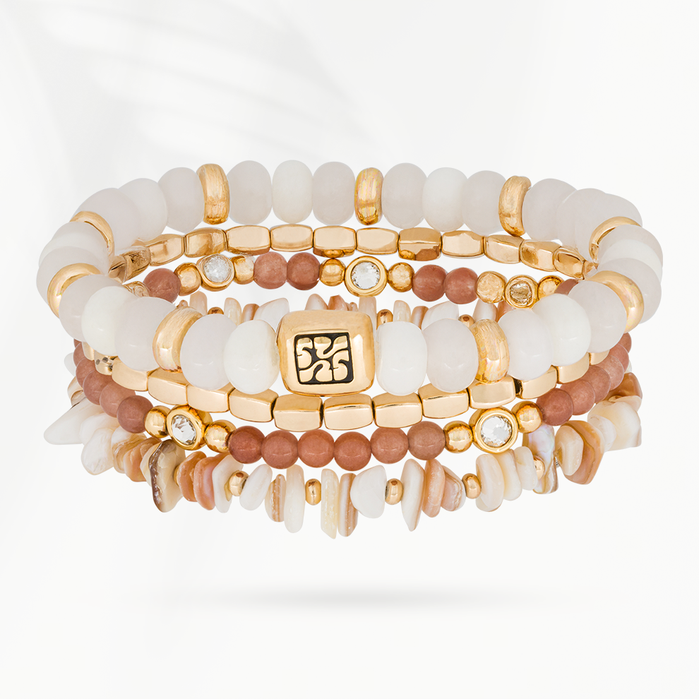 Armbandenset Blush van SummerGear met vier armbanden van witte ovale kralen, zachtroze natuurstenen kralen, schelpdetails en goudkleurige accenten.