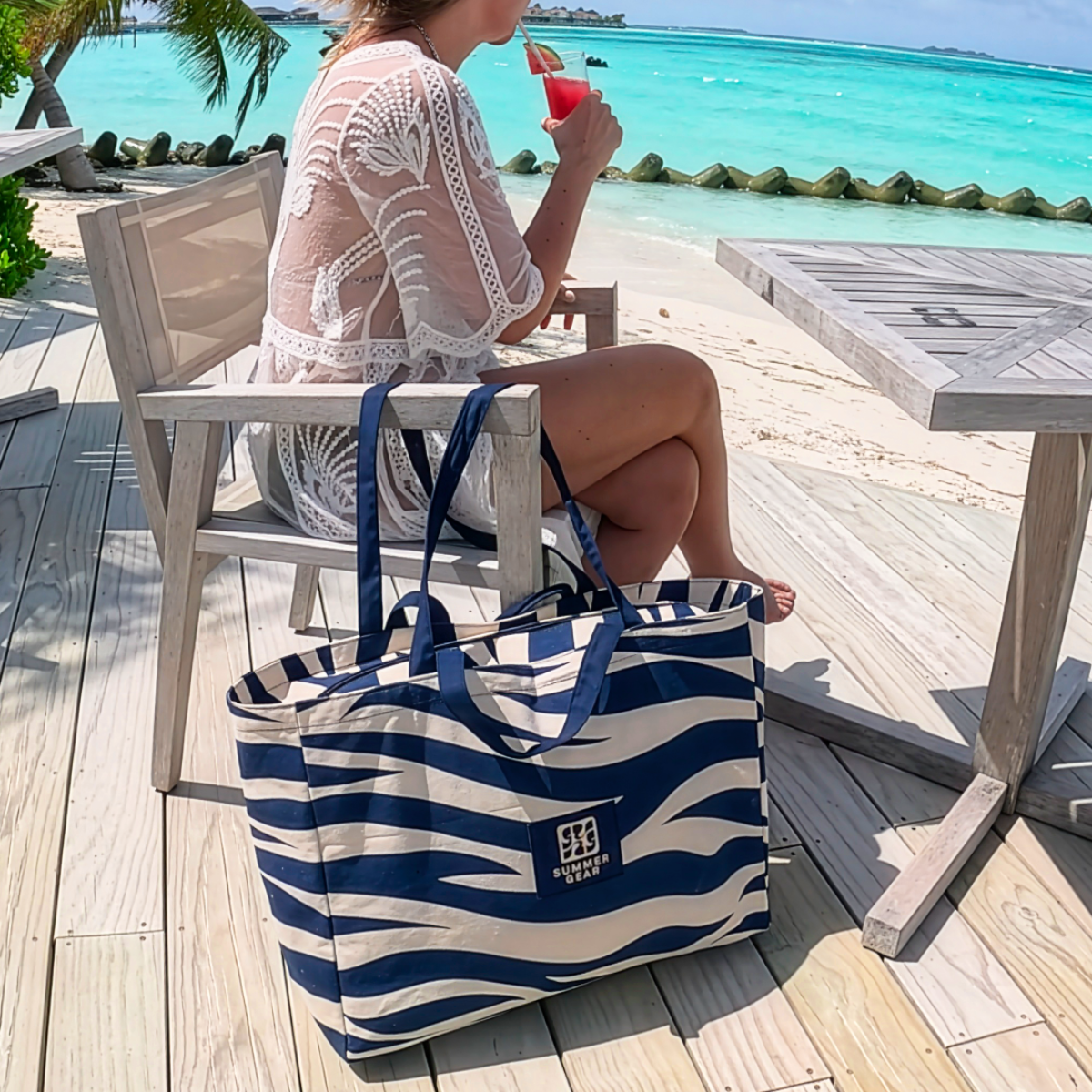 Canvas strandtas op terras bij zee met strandlaken erin, ruime beach bag voor strand en dagelijks gebruik
