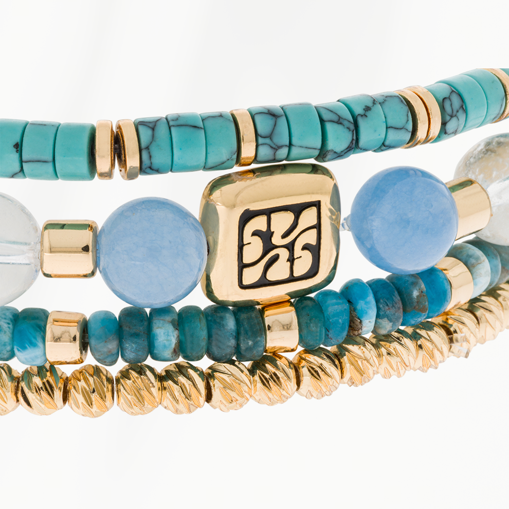 Close-up van de Blue Coast armbandenset van SummerGear met turquoise kralen, lichtblauwe natuurstenen kralen en goudkleurige details.