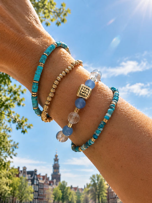 Armbandenset Blue Coast van SummerGear met blauwe en turquoise kralen en goudkleurige details, gedragen om de pols.