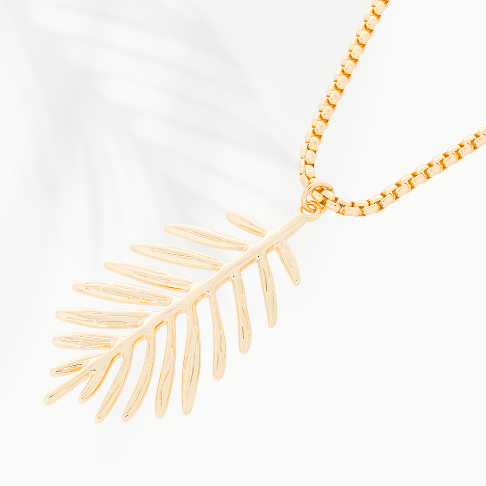 Close-up van de goudvergulde damesketting Palm Leaf van SummerGear met open palmbladhanger, smalle blaadjes en fijne schakels