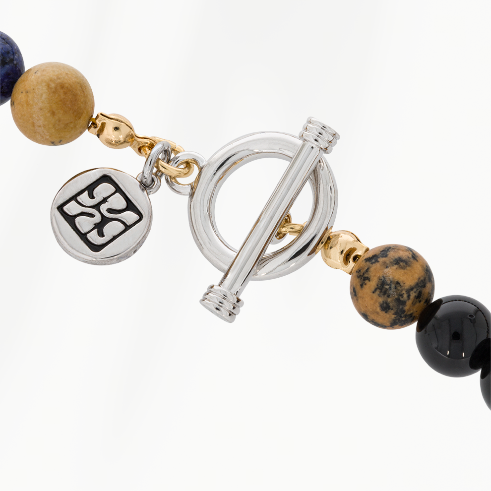 Detail van de zilverkleurige roestvrijstalen sluiting van de Lava Earth kralenketting voor heren, met ronde SummerGear-bedel en goudkleurige accenten.