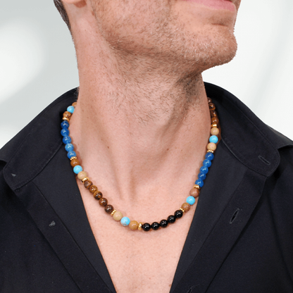 Ocean Blue kralenketting voor heren met blauwe, turquoise, bruine en zwarte kralen, gedragen bij een zwart overhemd. Kopiëren