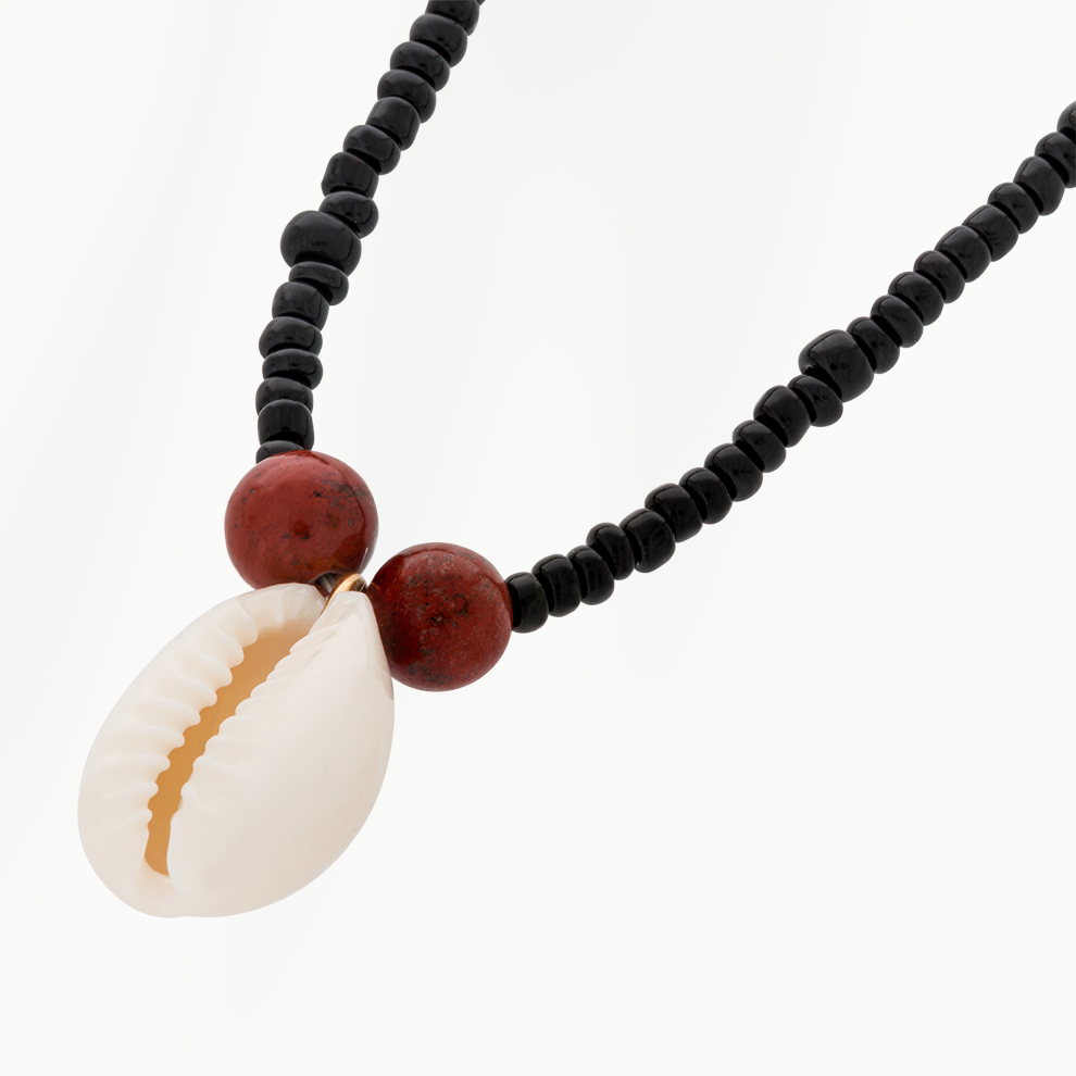 Detailfoto Sand Drop kralenketting met ivoorwitte schelphanger, goudkleurig detail en roodbruine kralen
