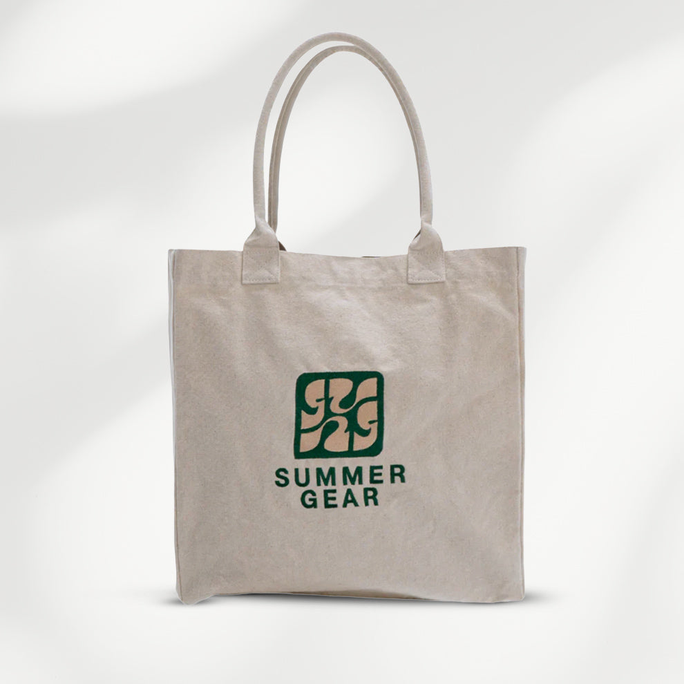Naturelkleurige canvas shopper van SummerGear met lange schouderhengsels en donkergroen logo op de voorkant.