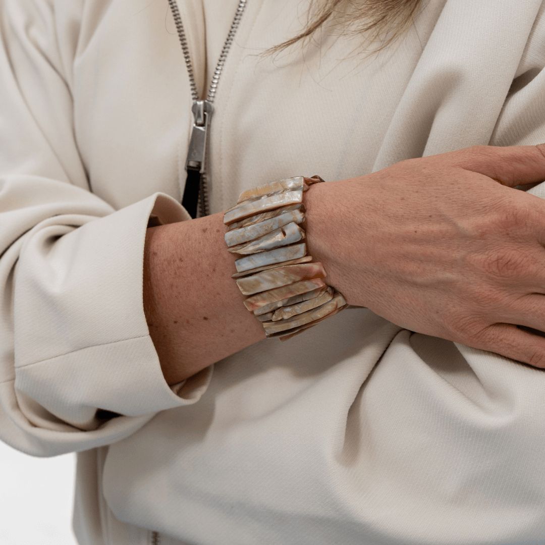 Brede licht beige parelmoer armband Sand Shell gedragen om de pols